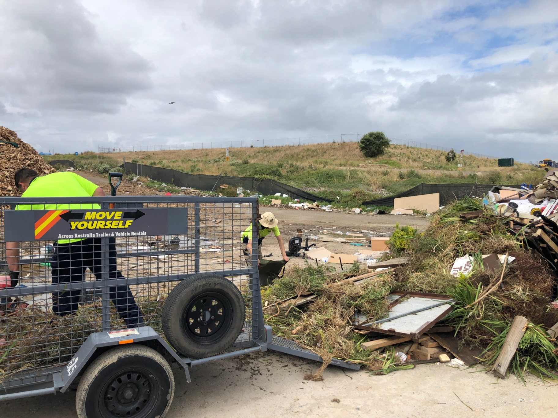 Brigade members in hi-vis unloading green waste at the tip